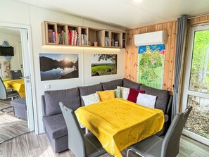 A cozy room with a gray sofa, a yellow tablecloth-covered table, and a bookshelf filled with books. - Tiny Haus Conny by Interhome (Wemding)