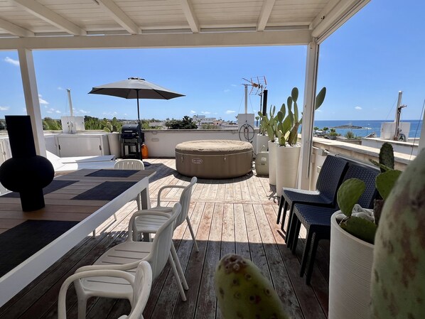 Relax outdoors with a scenic view of the water from this covered deck, featuring a grill and comfortable seating.