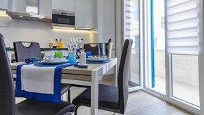 A modern kitchen with white cabinets, a microwave, and a dining area with a table set for two. - TSG 4 (Apartment + Extra Overview Terrace) (Ugento)