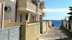 A multi-story building with balconies, a clear sky, and a view of the sea. - TSG 4 (Apartment + Extra Overview Terrace) (Ugento)