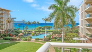 A resort with a pool, palm trees, and a view of the ocean.