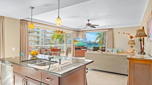 A modern kitchen with a marble countertop, a built-in sink, and a dining area with a table and chairs.