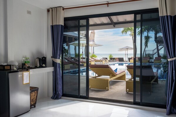 Une pièce dotée d’une porte vitrée donnant sur un espace piscine, aménagé avec des chaises longues et des parasols.