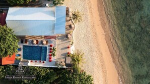 Un resort con piscina, playa y un edificio de techo rojo.