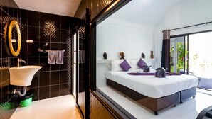 Un dormitorio moderno con una cama grande, un tocador con espejo y vista a zonas verdes.