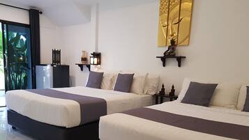 Habitación de hotel con dos camas, un ventanal con vistas a zonas verdes, una estatua de Buda montada en la pared y una obra de arte dorada decorativa.
