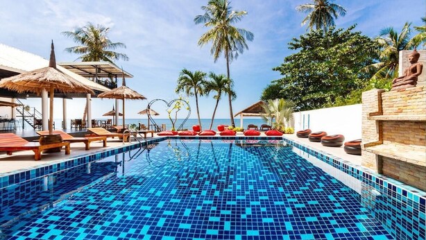 Un área de piscina con sillas de descanso, una estatua y palmeras.