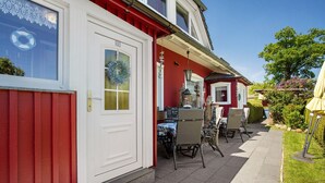 A red building with a white door, outdoor seating with chairs and tables, and a small garden area. - Apartment 'Fewo 12 - Halbinsel Darss - Ostsee' with Private Terrace, Shared Garden and Wi-Fi (Wieck am Darß)