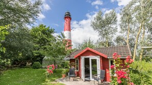 Un faro rojo y blanco con un pequeño edificio rojo en primer plano.
