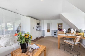 A modern interior with a living area, kitchen, and dining space. - Apartment 'Südwest' with Shared Terrace, Private Garden and Wi-Fi (Pellworm)