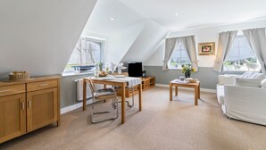 Une chambre moderne de style loft, dotée d’un coin repas, d’un canapé, d’une télévision et de grandes fenêtres.