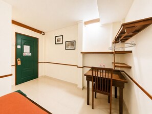 Um corredor com uma porta verde, uma mesa pequena com cadeiras e uma escada de madeira.