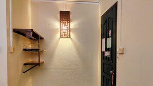 Un pasillo estrecho con un panel decorativo en la pared, una puerta con cerradura y un pequeño estante.