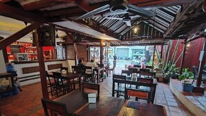 Un restaurante con mesas y sillas de madera, suelo de baldosas y un ventilador de techo.