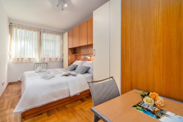 A bedroom with a bed, bedside table, and a window with curtains.
