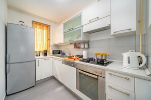 A modern kitchen with a refrigerator, microwave, stove, oven, and various kitchen appliances.
