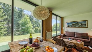 Un coin repas avec une table dressée pour deux personnes, un canapé et un tableau accroché au mur.