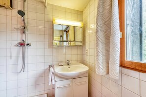 A bathroom with a white sink, mirror, and shower.