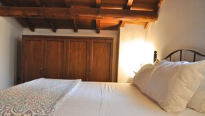 Un dormitori amb un llit, un armari de fusta i una finestra amb llum natural.