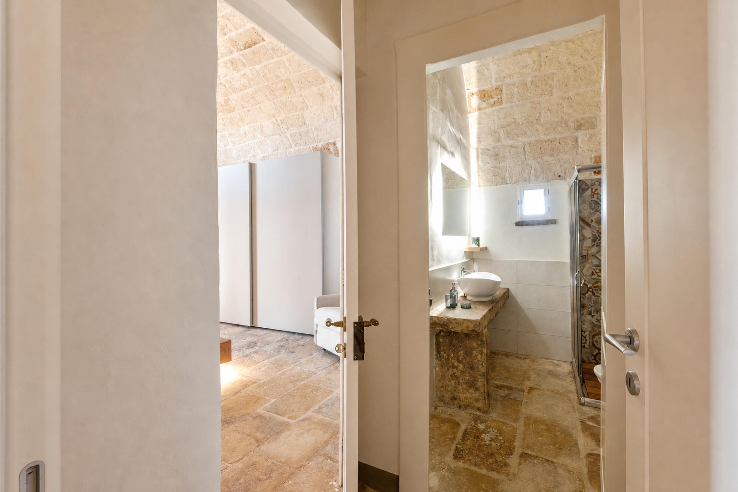 Une salle de bain avec un sol en pierre, un lavabo et un espace douche.