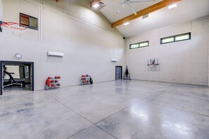 Eine geräumige Indoor-Basketballhalle mit zwei Basketballkörben, einer Uhr und einer Klimaanlage an der Wand.