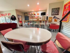 Ein Restaurant mit einem großen runden Tisch, roten Stühlen und Sportmemorabilien an den Wänden.