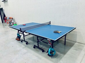 Ein blauer Tischtennis-Tisch mit Netz, Ball und Schlägern.