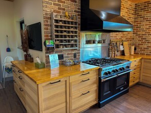 Een keuken met een gasfornuis, oven en een bakstenen muur.