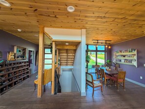 Una habitación amplia con techo de madera, un comedor con sillas y una mesa, y una estantería con frascos.