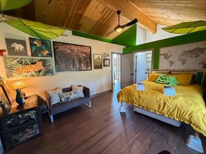 Una habitación con una cama, un sofá, suelo de madera y un mapa mundial en la pared.