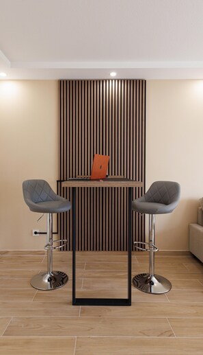 A modern room with two bar stools, a wooden slat wall, and a laptop on a table. - Apartment 'Wohnung Mit Terrasse Nähe Airport' with Private Terrace and Wi-Fi (Schönefeld)