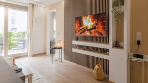 Ein modernes Wohnzimmer mit Flachbildfernseher, Holzvertäfelung und einer Schiebetür zu einem Außenbereich.