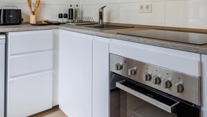 Eine moderne Küche mit weißen Schränken, einem Einbauofen und einer Arbeitsplatte mit Toaster und Besteck.