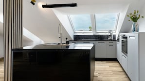 Une cuisine moderne avec un îlot central noir, des armoires blanches et une lucarne.
