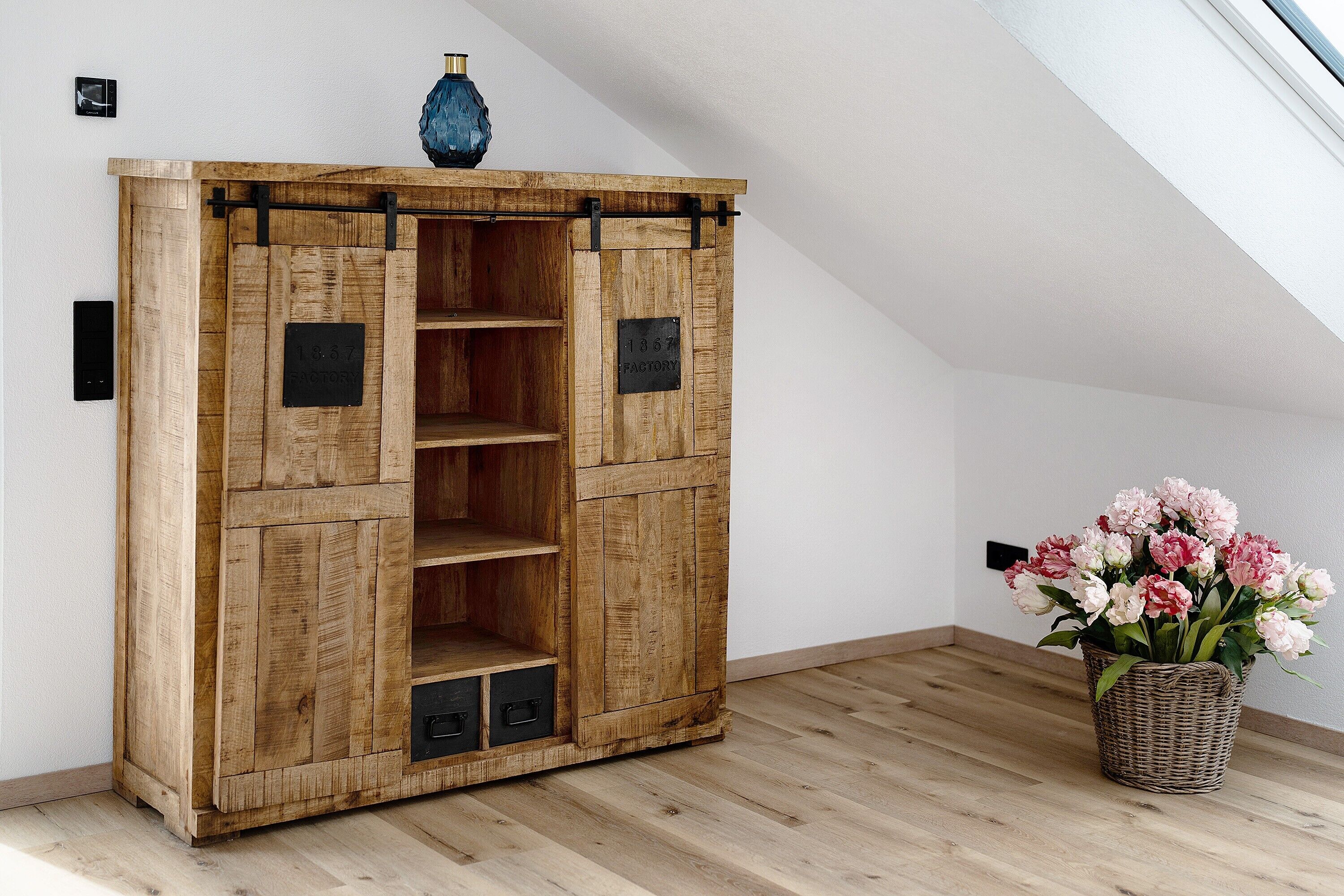 Un meuble en bois sur lequel sont posés un vase et un panier de fleurs.