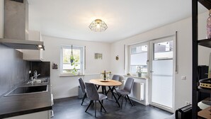 Een moderne keuken met een centraal eiland, inbouwapparatuur en een eethoek met stoelen.