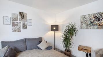 Un salon moderne avec un canapé gris, une plante en pot et des œuvres d’art murales.