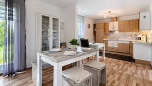 Une cuisine moderne avec des meubles en bois, une table à manger avec des bancs, et une vue sur l’extérieur.