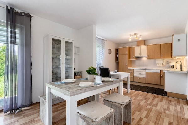A modern kitchen with wooden cabinets, a dining table with benches, and a view of the outdoors.