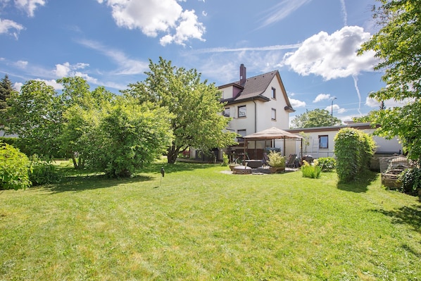 Une maison avec un grand jardin, une terrasse et une cheminée.