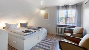 Une chambre avec un lit en mezzanine, un radiateur, une fenêtre avec des rideaux et une chaise.