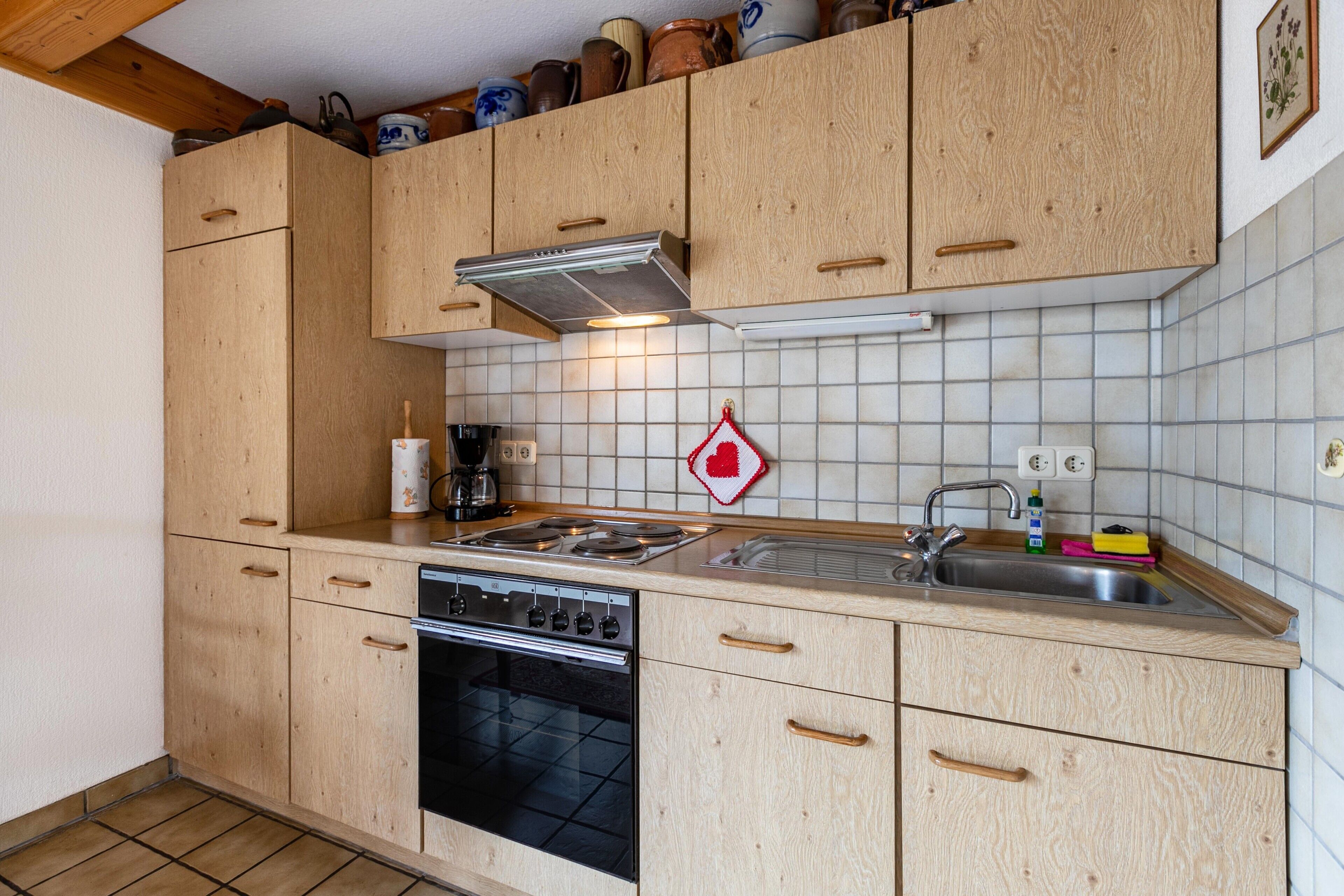 A kitchen with wooden cabinets, a stove, a sink, and a tiled backsplash.
