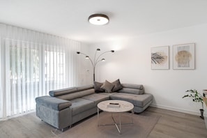 A modern living room with a grey sectional sofa, a round coffee table, and two abstract wall art pieces.