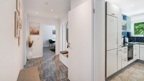 A modern kitchen with white cabinets, a built-in oven, and a large window.
