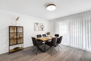 A dining area with a wooden table, black chairs, a glass cabinet, and a vase with flowers.