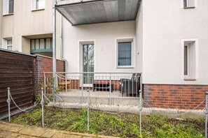 Un edificio residenziale con un patio recintato, un muro in mattoni e facciata bianca.