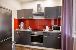 Una cucina moderna con mobili scuri, un forno in acciaio inossidabile, un microonde e una macchina per il caffè.
