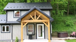 Une maison à deux étages dotée d’un porche couvert, d’un jacuzzi et d’un espace barbecue.