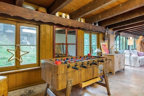 A wooden-floored room with a foosball table, large windows, and a rustic interior.
