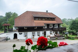 A two-story building with a tiled roof, a balcony, and a small porch area.